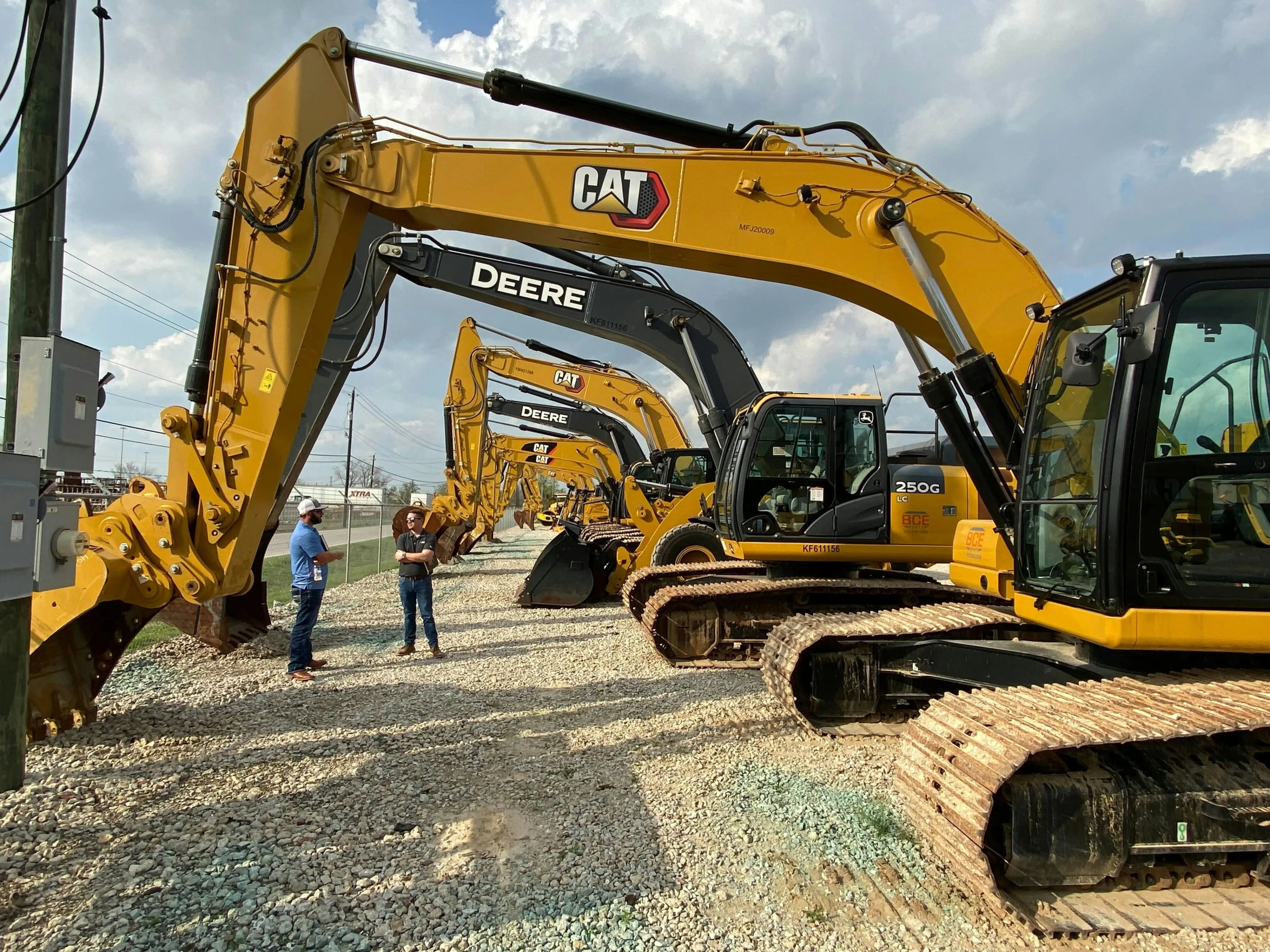 Equipment rental yard with excavators and two workers