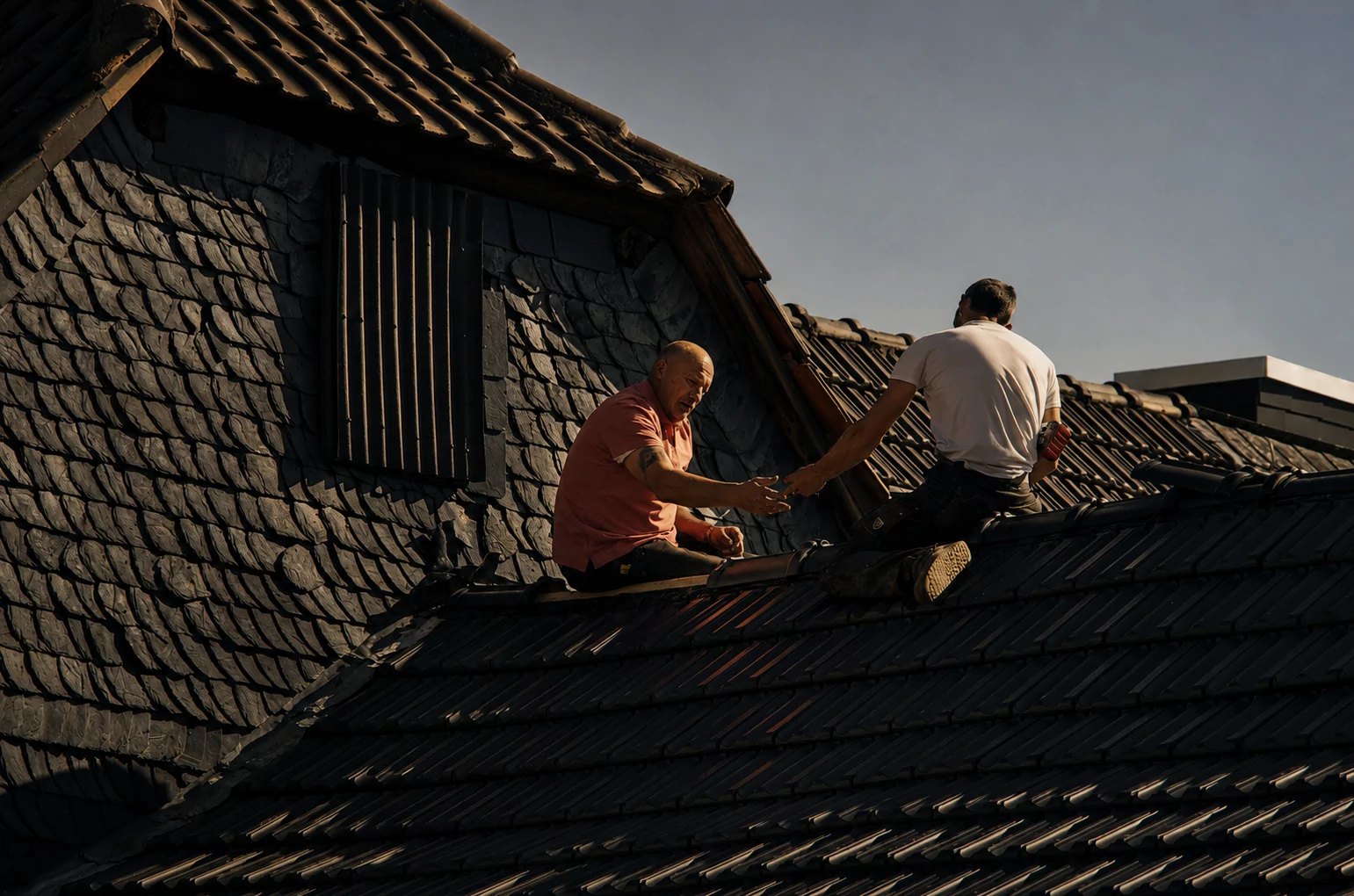 Commercial roofing foreman reviewing a tablet in golden-hour light